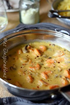 a bowl of soup with carrots and other food items on the table next to it