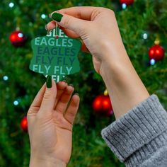 two hands holding up a green christmas ornament that says eagles, eagles fly it