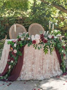 the table is set up with two chairs and flowers on it, along with candles