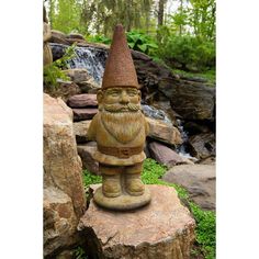 a garden gnome statue sitting on top of a rock in front of a pond and waterfall