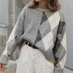 a woman is walking down the street wearing a gray and white checkerboard sweater