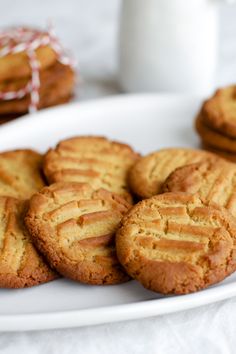 cookies on a white plate next to a glass of milk