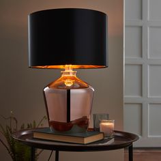 a table with a lamp on top of it and some candles in front of it