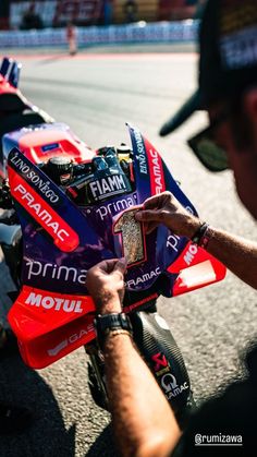 a man holding onto a red and blue motorcycle