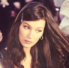 a close up of a person with long hair and wearing earring on her head