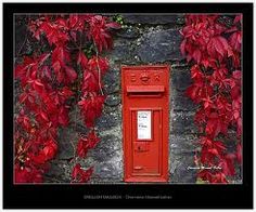 an old fashioned red post box in front of a stone wall with ivy growing on it