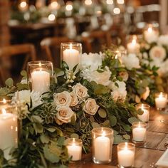 a table with candles, flowers and greenery is set up for a wedding reception