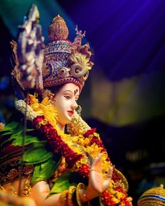 the statue is dressed in an elaborate costume and headdress with flowers on it