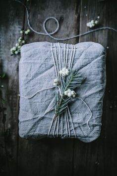 a present wrapped in grey linen with white flowers on it and twine around the edge