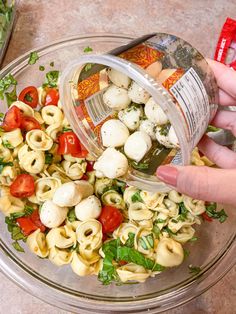 a person pouring dressing into a bowl of pasta salad