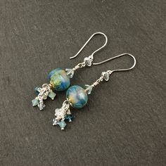 "This new pair of lampwork earrings features my handmade lampwork beads in a beautiful iridescent opalesque blue. I have embellished these beads with coordinating Swarovski crystals and sterling silver beads, then dangled them from sterling silver wire that has a light blue topaz setting. These one of a kind earrings measure 2.5\" from top to bottom, and will arrive beautifully packaged. To view more jewelry and handmade glass beads, click here: http://www.stonedesignsbysheila.etsy.com" Iridescent Light, Crystal Bead Jewelry, Lampwork Earring, Handmade Lampwork Bead, Handmade Glass Beads, Lampwork Glass Beads, Topaz Gemstone, Beaded Jewelry Diy, Earrings Sterling Silver