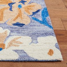 a blue and yellow rug with flowers on the floor next to a hardwood flooring