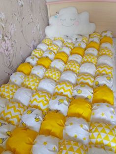 a bed with yellow and white sheets on it, next to a stuffed animal in the corner