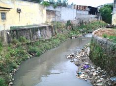 there is a small river running through an alley way with buildings on either side and trash strewn all over the street