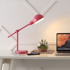 a pink desk lamp sitting on top of a white table next to a laptop computer