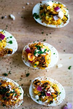 deviled eggs topped with various toppings on a wooden table