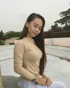 a young woman sitting on top of a cement floor