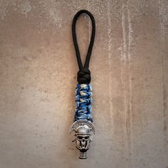 a silver and blue beaded skull on a black cord