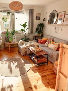 a living room filled with furniture and lots of plants in the window sills