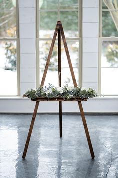 a wooden easel with succulents on it in front of a window