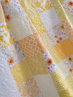 a yellow and white quilt with flowers on it