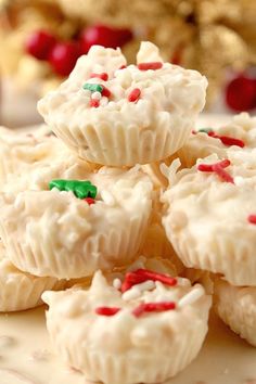 small white cupcakes with sprinkles on a plate next to christmas decorations