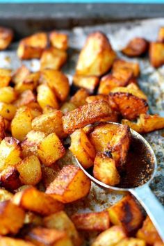 some food that is on top of a pan with spoons in it and potatoes