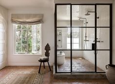 a bathroom with a shower, toilet and window in the corner next to it is tiled flooring