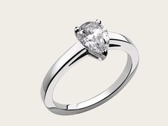 a white gold engagement ring with a pear shaped diamond in the center, on a white background