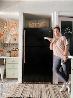 a woman standing in front of a black refrigerator