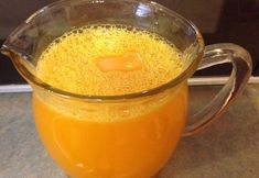 a pitcher filled with orange juice sitting on top of a counter next to a microwave