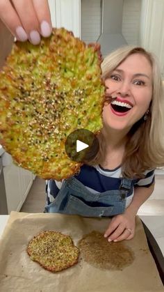 a woman holding up a pizza in front of her face and smiling at the camera