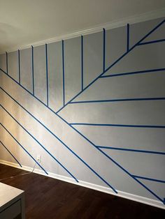 an empty room with blue lines painted on the wall and hard wood flooring in front of it