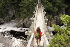 a woman walking across a bridge over a river