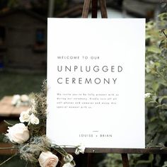 an unplugged ceremony sign sitting on top of a easel with flowers