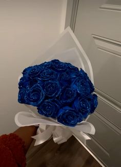 a bouquet of blue roses sitting on top of a wooden floor next to a door