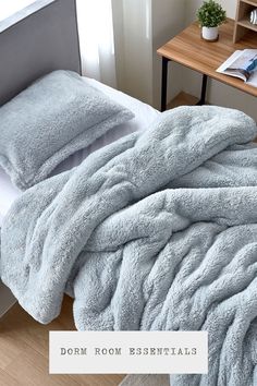 a bed with two pillows on top of it next to a book shelf and desk