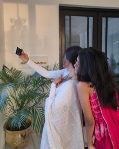 two women are standing in front of a door and taking pictures with their cell phones