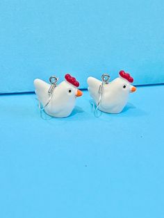 two white ceramic chickens with red hats on their heads are sitting next to each other