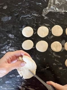 the person is using a knife to cut dough into small circles