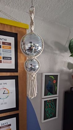 there is a mirror ball hanging from the ceiling in front of pictures on the wall