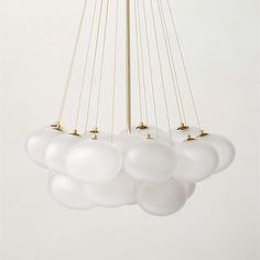 a chandelier with white glass balls hanging from it's brass frame arms