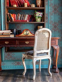 a chair sitting in front of a desk with books on it and a book shelf behind it