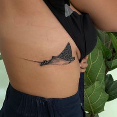 a woman's stomach with a small tattoo of a stingfish on the side