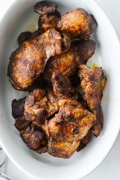 a white bowl filled with cooked chicken on top of a table