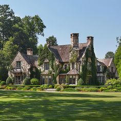 a large house with many windows and ivy growing on it's walls, surrounded by lush green grass