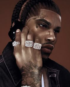 a man with tattoos and piercings on his face is holding his hand to his ear