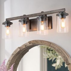 a bathroom vanity light with three lights on the side and an arched mirror above it