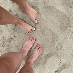 two people with pink and white toenails standing in the sand