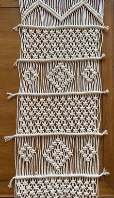 a close up of a piece of white crocheted material on a wooden surface